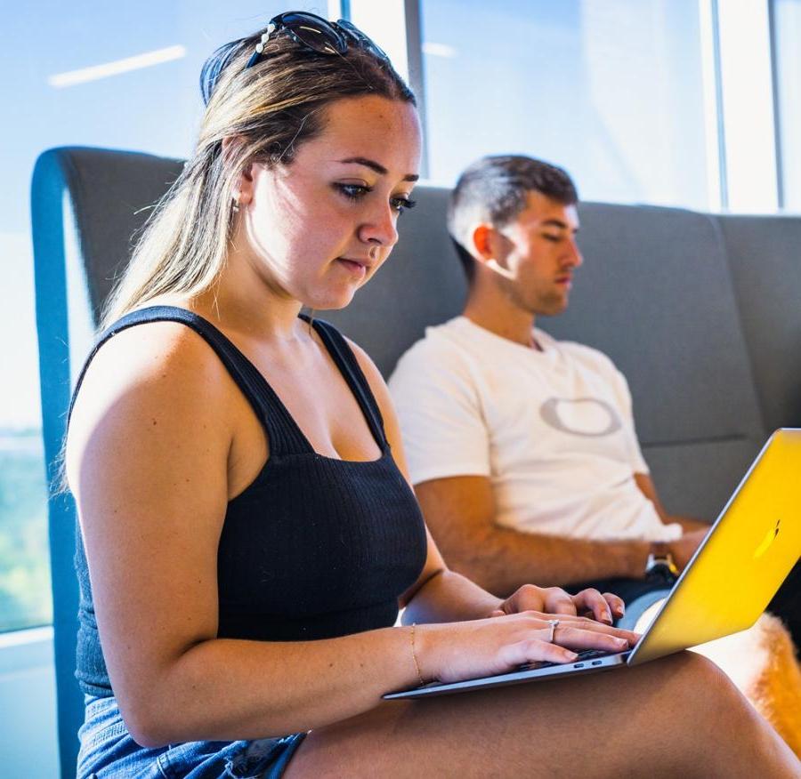 A student looking at her computer in a student area on campus