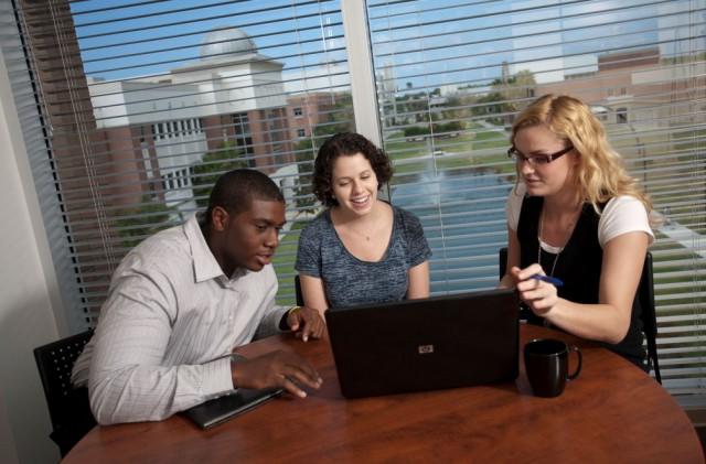 Three students looking at a laptop