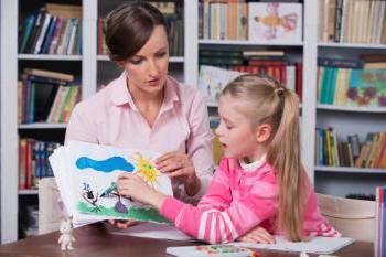 A young girl pointing a crayon at her drawing