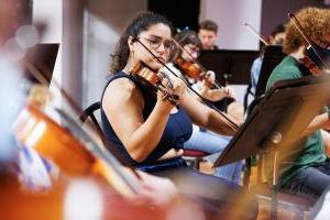 Student playing the violin in the string orchestra