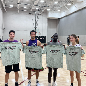 Students from the champion intramural basketball team smiling and holding shirts that read 