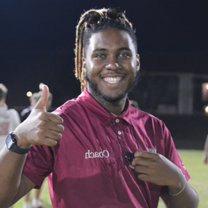 A student official smiling and giving a thumbs up at an intramural sports competition.